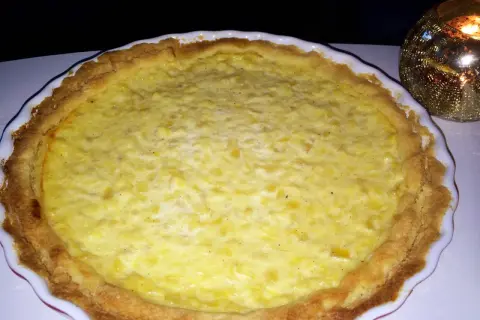 En gyllene ananaspaj glutenfri med en krämig fyllning. En ljuslykta glimmar i bakgrunden.