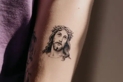 Ein Porträt von Jesus mit Dornenkrone, ein Beispiel für minimalistische Tattoos, auf einem Arm.