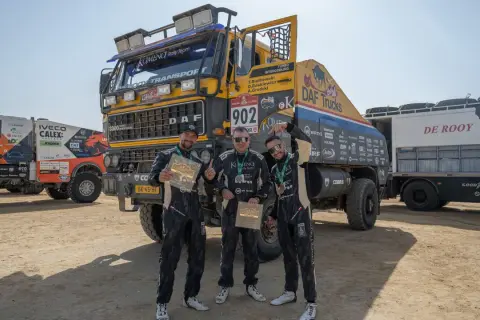 Trzej członkowie zespołu KAMENA Rally Team pozują z pucharami przed ciężarówką DAF.