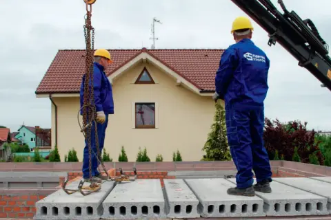 Pracownicy montują prefabrykowane płyty, prezentując różne rodzaje stropów. Budowa domu z wykorzystaniem nowoczesnych technologii.