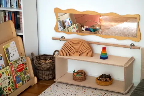 Holzspielzeug, Bücher und Körbe für ein gemütliches Kinderzimmer einrichten. Ein Holzregal mit Regenbogen und Stapelturm.