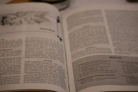 En öppen bibel med texten "Jesaja" synlig. En bok i bibeln som berättar om Guds budskap.