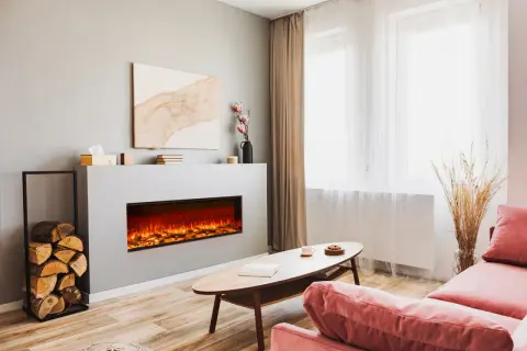 Nowoczesny salon z dużym kominkiem elektrycznym, który tworzy przytulną atmosferę. Obok stos drewna.