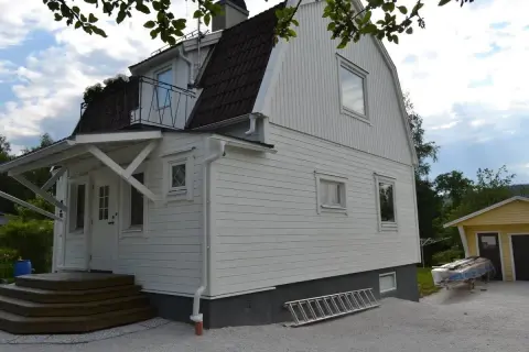 Vitt hus med ny fasad, trappa och en stege redo för arbete.