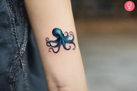 Un pulpo azul vibrante, un ejemplo de tatuaje microrealismo, se posa en un brazo.