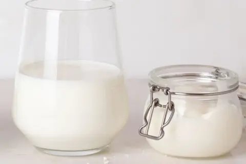Un verre de lait et un pot de lait de beurre, prêts pour une recette gourmande.