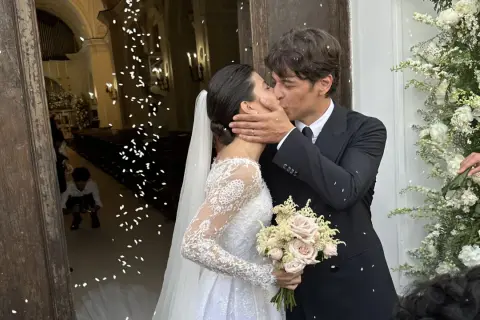 Alessandra Mastronardi e il suo sposo si baciano fuori dalla chiesa, tra petali di fiori e un'atmosfera di gioia per il loro matrimonio.