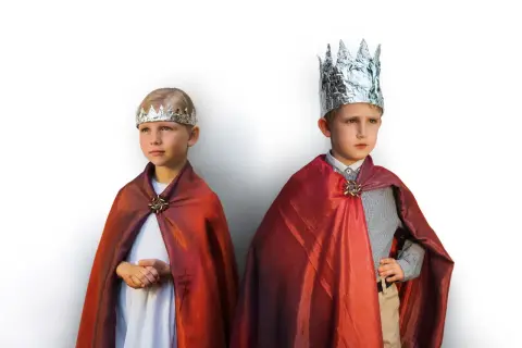 Dwóch chłopców w strojach hiszpańskich królów, z błyszczącymi koronami i czerwonymi pelerynami.