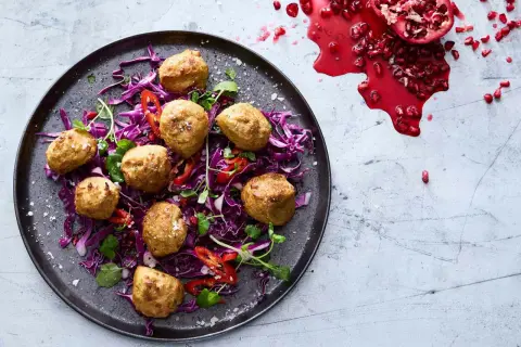 Falafel i airfryer serveras på en bädd av rödkål med strimlad paprika och granatäpple.