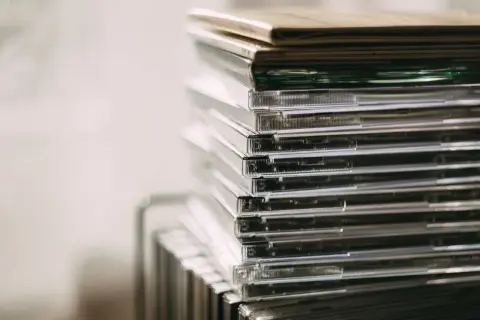 Stos przezroczystych pudełek z płytami CD, idealny do przechowywania nowości płytowych.