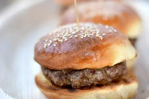Mini burgery na puszystych bułkach do burgerów, posypane sezamem, gotowe do podania.