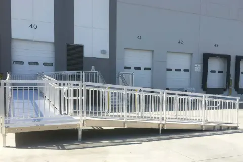 A modular wheelchair ramp system is installed outside a warehouse, providing accessibility to loading docks. This shows how to build a wheelchair ramp for easy access.