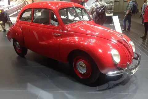 En glänsande röd ifa bil står på ett mörkt golv. Bilen har en rundad form och kromade detaljer.