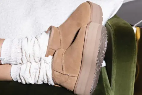 Pieds chaussés de bottes en daim UGG, avec des chaussettes blanches torsadées. Un aperçu de l'entretien chaussure daim.