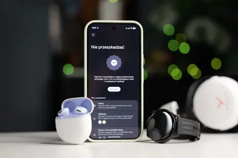Smartfon z włączonym trybem nie przeszkadzać Samsung, obok słuchawki i smartwatch.
