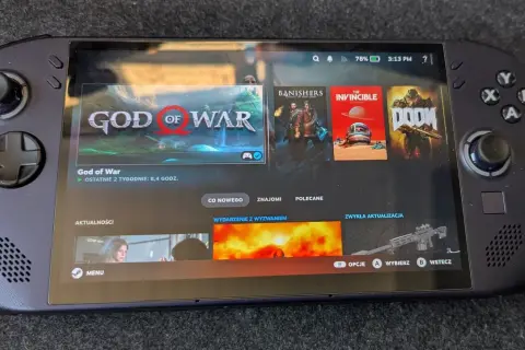 Przenośna konsola Steam Deck z systemem SteamOS 3, wyświetlająca okładki gier: God of War, Banishers, The Invincible i Doom.