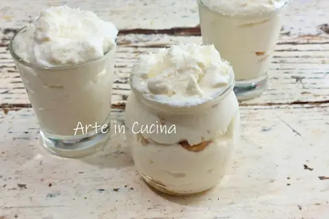 Délicieux tiramisu coco crémeux, servi dans des verrines et un pot en verre, parsemé de copeaux de noix de coco.