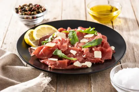 Carpaccio wołowe jak jeść: cienkie plastry surowej wołowiny z parmezanem, rukolą i cytryną. Idealne na lekki posiłek.