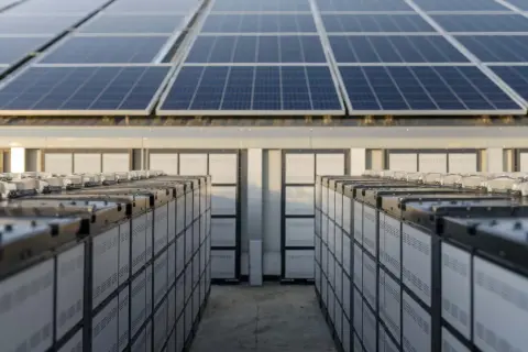 Rozbudowa instalacji fotowoltaicznej: rzędy baterii magazynujących energię pod panelami słonecznymi.