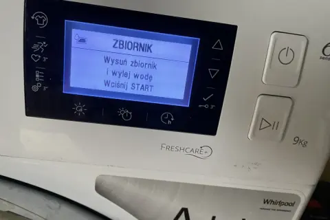 Na wyświetlaczu pralki komunikat: "ZBIORNIK. Wysuń zbiornik i wylej wodę. Wciśnij START". Dużo wody w pojemniku na skropliny.