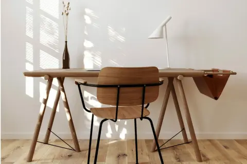 Scrivania in legno chiaro con sedia, lampada bianca e vaso. Perfetti colori da abbinare al legno chiaro per un ambiente luminoso e naturale.