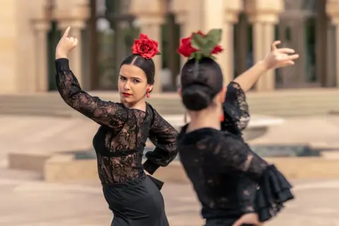 Una sevillana flamenca, con rosa roja en el pelo y pendientes a juego, baila con pasión.
