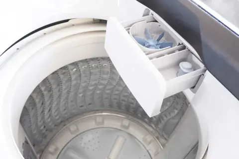 Cassetto detersivo lavatrice aperto, mostra come usare il detersivo liquido. La vaschetta è pronta per il bucato.