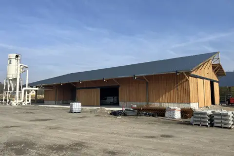 Nouveau bâtiment en bois, prêt à accueillir un atelier de menuiserie bois. Une tour de dépoussiérage est installée à côté.