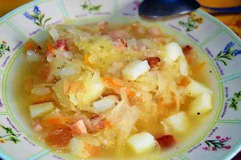 Gęsty, sycący kapuśniak z ziemniakami i kawałkami wędzonki, podany w ozdobnej misce.
