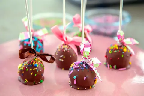 Chokladöverdragna cake pops med färgglada strössel och fina band. Perfekta för ett kalas!