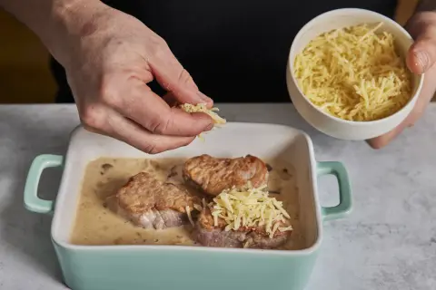 Zarte schweine medaillons in cremiger Sauce werden mit geriebenem Käse bestreut.