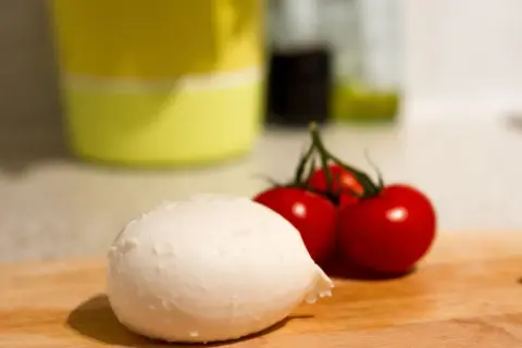 Frische Mozzarella und Kirschtomaten auf einem Holzbrett. Perfekt für eine leichte Mahlzeit während der Schwangerschaft.