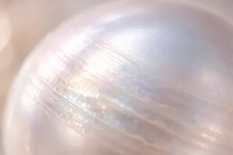 Detalle de una perla iridiscente, mostrando sus líneas naturales. Imagina limpiar perlas con bicarbonato para devolverles su brillo.