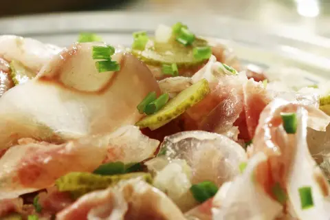 Ein deftiger Ochsenmaulsalat mit Gurken und Zwiebeln, garniert mit Schnittlauch. Perfekt für ein herzhaftes ochsenmaulsalat rezept.