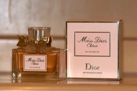 Elegancka butelka i pudełko perfum Miss Dior Chérie, ozdobione złotą kokardką, emanują luksusem.