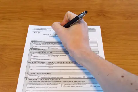 Dłoń z długopisem wypełniająca polski formularz podatkowy PCC-3/A.