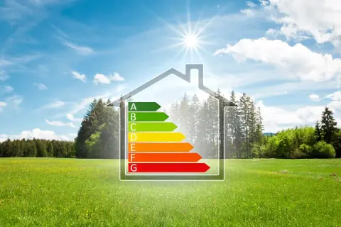 Casa con classe energetica A, simbolo di edilizia sostenibile, immersa in un prato verde sotto un cielo azzurro.
