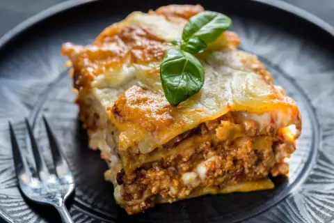 Une part de lasagne maison, dorée et gratinée, garnie de viande et de béchamel. Parfaite pour une recette lasagne réussie.