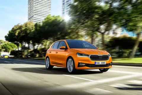 Pomarańczowa Skoda Fabia jedzie po mieście. Idealny samochód, by nauczyć się, co trzeba umieć na pierwszą jazdę.