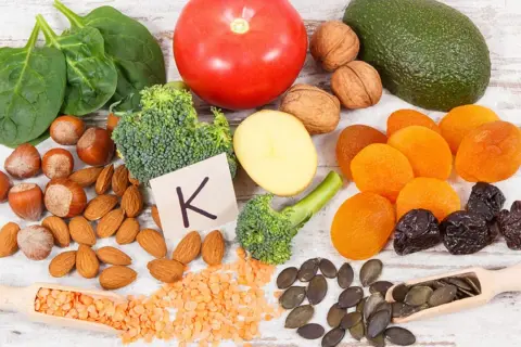 Gesunde Lebensmittel reich an Vitamin K, wichtig für die Schwangerschaft: Spinat, Brokkoli, Avocado, Nüsse, Trockenfrüchte.