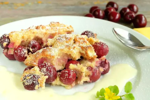 Zwei Portionen Kirschenmichel, ein köstliches Dessert, serviert mit Vanillesauce und bestäubt mit Puderzucker. Ein perfektes Kirschenmichel Rezept.