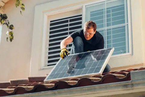 Hombre instala panel solar en tejado. ¡Qué frustración que mi comunidad no me deja poner placas solares!