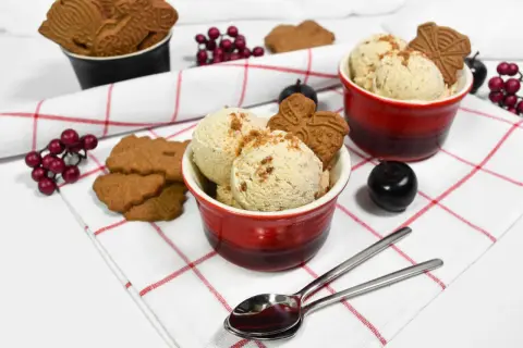 Leckeres Spekulatius Eis selber machen? Hier sind zwei Schalen mit cremigem Eis, garniert mit Spekulatius und roten Beeren.