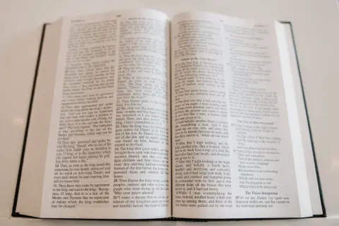 Otwarta Biblia, na jej stronach widnieje tekst, który może być fragmentem pieśni lub hymnu kościelnego.