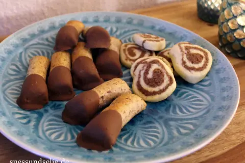 Mandelstangen mit Marzipan und schokoladenüberzogenen Keksen auf blauem Teller.