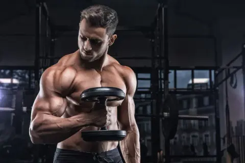 Uomo muscoloso in palestra con manubrio, focus sulla definizione muscolare, integrando la creatina per massimizzare i risultati.