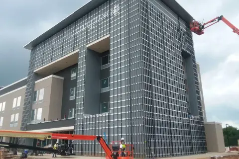 Instalación de sistemas de fachadas ventiladas en edificio moderno. Obreros en plataformas elevadoras trabajan en la colocación de paneles.