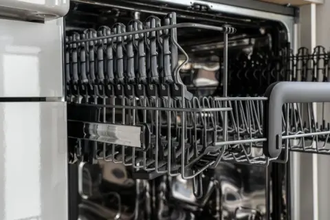 Wnętrze zmywarki z wysuniętymi koszami. Zmywarka nie grzeje wody, co może być problemem dla czystości naczyń.