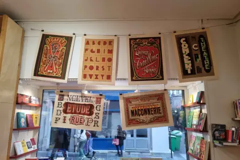 Affiches vintage avec un alphabet décoratif, des publicités de café, de laines et de théâtre.