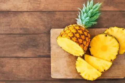 Saftige Ananas, frisch aufgeschnitten, liegt auf einem Holzbrett. Eine gesunde Wahl, die an den Geschmack von Ananas aus der Dose erinnert.